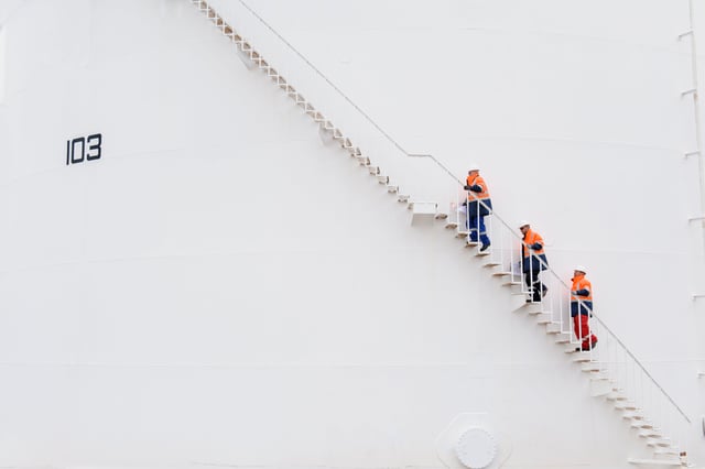 People in construction gear climbing up a ladder